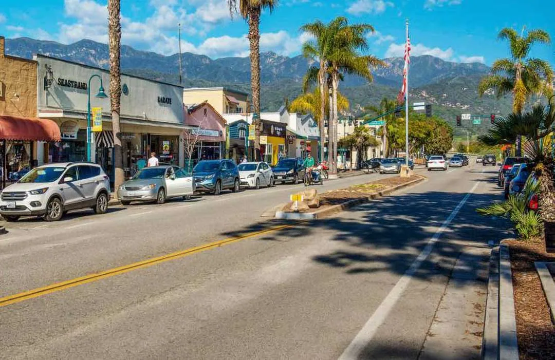 Downtown Carpinteria street with shops, palm trees, and mountains in view, service area for Plumber in Carpinteria.