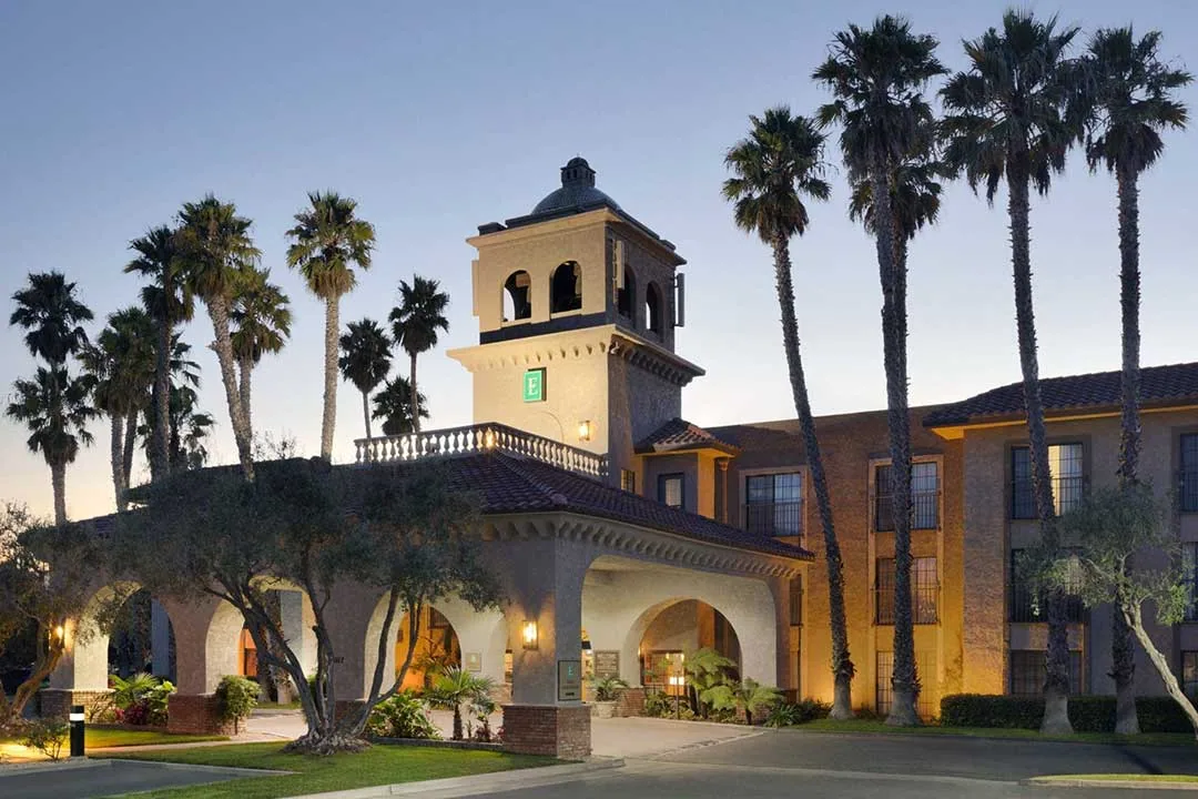 Spanish-style hotel with bell tower and palm trees at dusk in Lompoc, CA, service area for Plumber in Lompoc.