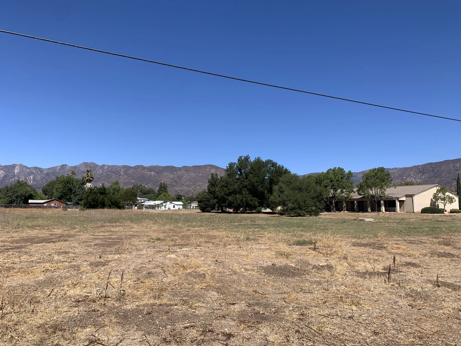 Open field in Meiners Oaks, CA with scattered trees, nearby homes, and mountain backdrop, service area for plumber in Meiners Oaks