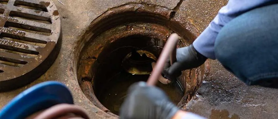 Commercial hydro-jetting Santa Barbara – plumber cleaning commercial drain with hydro-jetting hose, professional plumbing service.